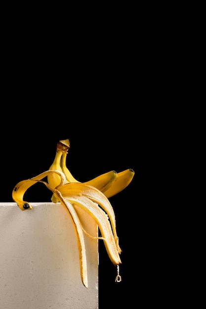 Een banaan en bananenschil op een witte blokstandaard