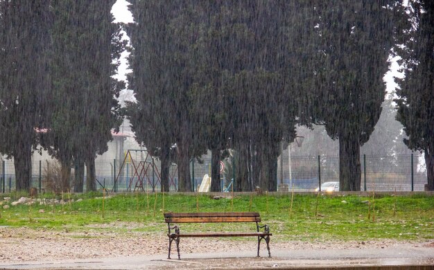 Foto een bank staat onder zware regen in het park.