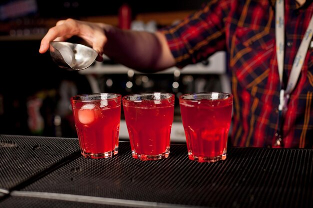 Een barman maakt aan de bar een cocktail met alcohol in een bar. Het concept van het nachtleven.