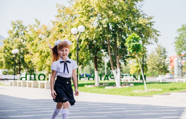 Een basisschoolleerling van een klein meisje heeft plezier op straat. Het kind gaat graag naar school.