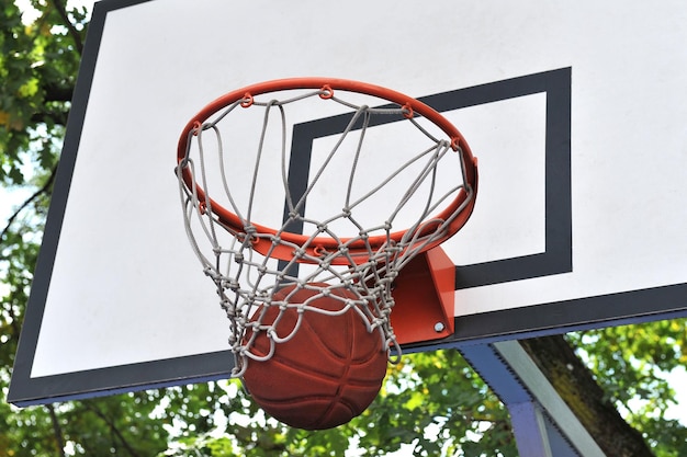 Een basketbal in een mand op een basketbalveld buiten