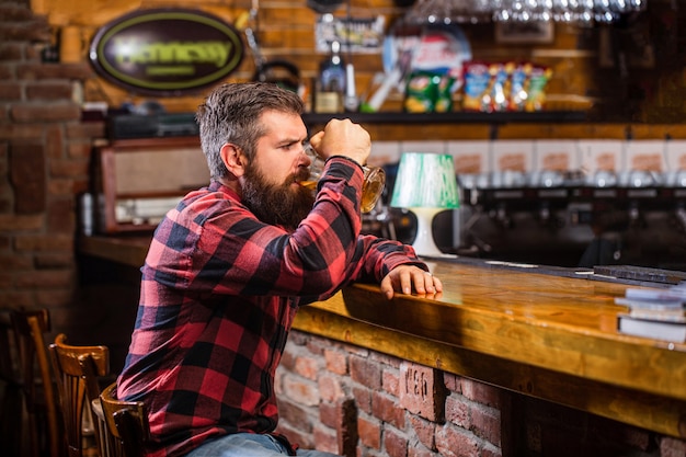 Een bebaarde man drinkt bier in een bar.