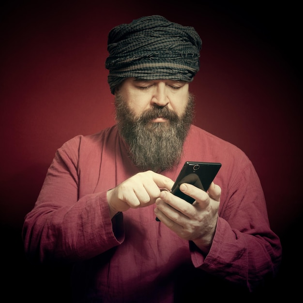 Een bebaarde man in een rood shirt en een tulbandvinger belt het telefoonnummer op een rode achtergrond