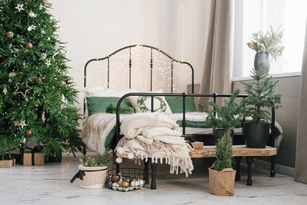 Een bed met een beige plaid en groene kussens een kerstkrans aan de muur een kerstboom Nieuwjaars winter interieur interieur De kamers zijn ingericht in Scandinavische stijl Stijlvolle knusse slaapkamer
