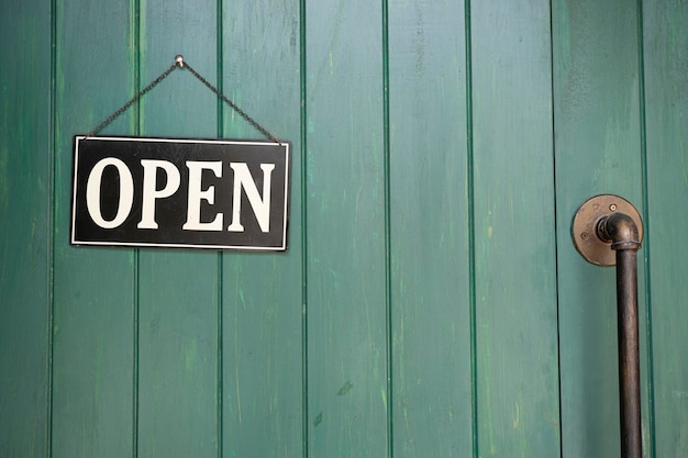 Een bedrijfsbord met de tekst 'Open' op café of restaurant hangt aan de deur bij de ingang