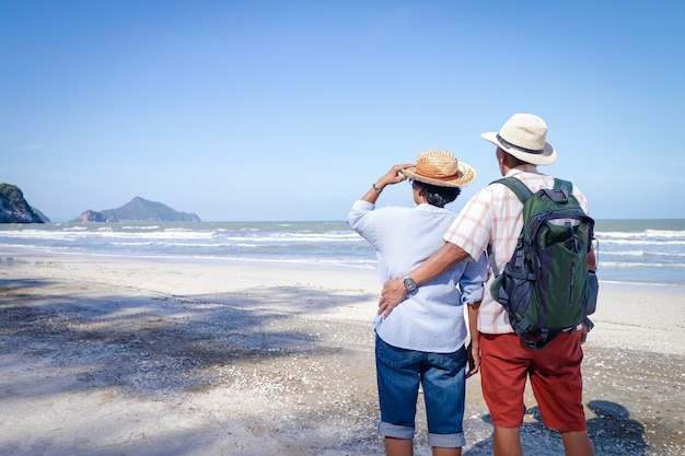 Een bejaarde Aziatische paar knuffelen elkaar op het strand