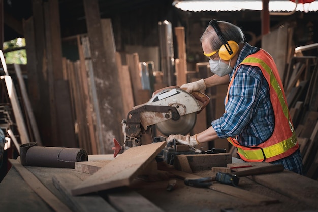 Een bejaarde timmerman bewerkt het hout met uiterste zorg