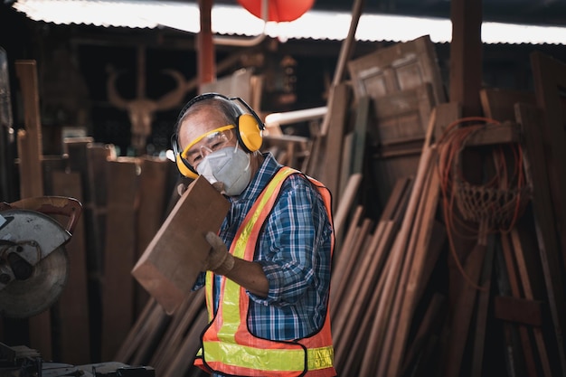 Een bejaarde timmerman bewerkt het hout met uiterste zorg