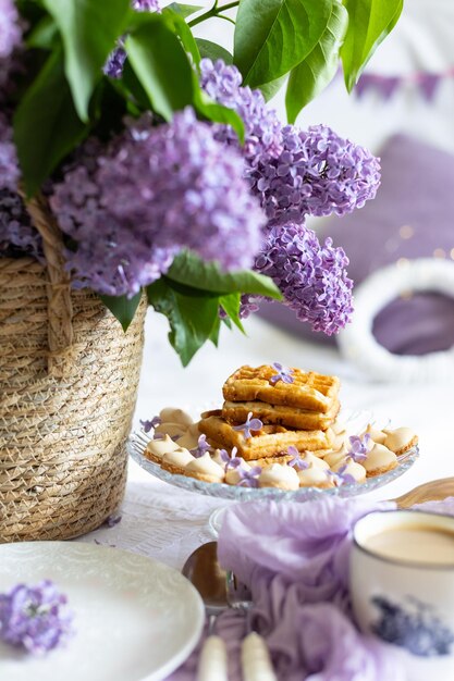 een beker met een warm drankje ontbijt met wafels en cakes een boeket lila in een vliezen mandje