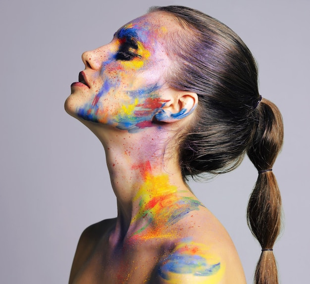 Een belangrijk moment hebben met haar make-up Studio-opname van een aantrekkelijke jonge vrouw met felgekleurde make-up tegen een paarse achtergrond