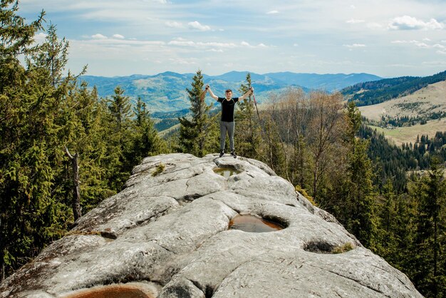 Een bergbeklimmer staat hoog in de bergen tegen de hemel, viert de overwinning en steekt zijn handen op.