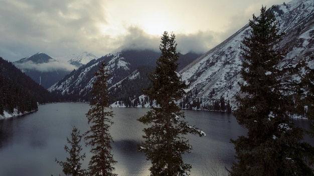 Een bergmeer in een winterbos. Drone-weergave van naaldbomen, spiegelglad water en wolken