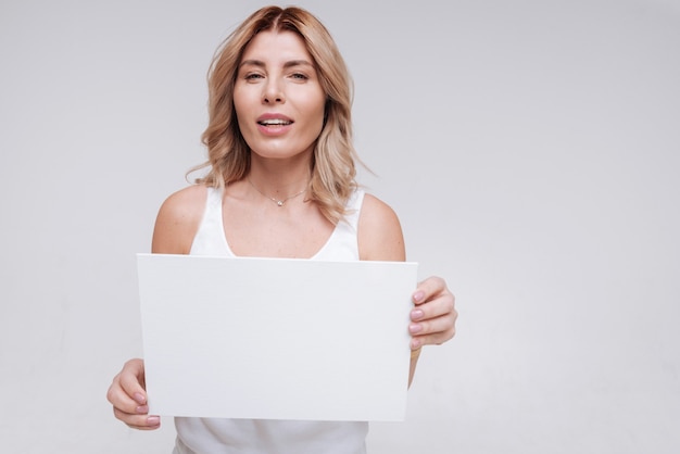 Foto een bericht verzenden. hypnotiserende bochtige toegewijde vrouw die een wit stuk papier demonstreert