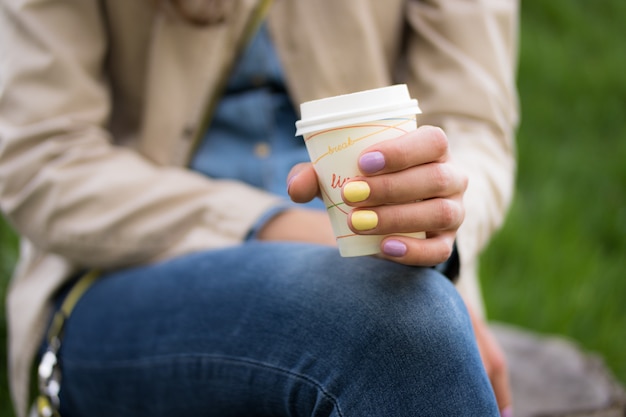 Een beschikbare koffiekop in een vrouwelijke handclose-up