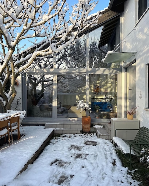 Een besneeuwde achtertuin met een terras en een tafel met een stoel en een tafel bedekt met sneeuw.