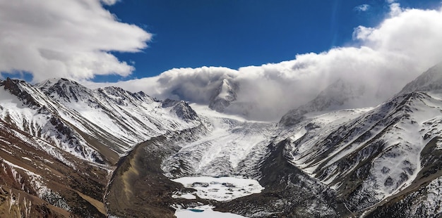 Een besneeuwde berg met een blauwe lucht en wolken op de achtergrond
