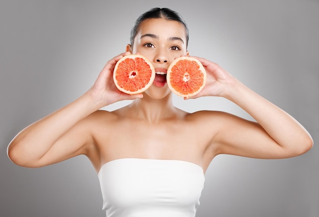 Een betere en stralende huid met een vitamine C-boost Studio-opname van een aantrekkelijke jonge vrouw die grapefruit tegen haar gezicht houdt tegen een grijze achtergrond