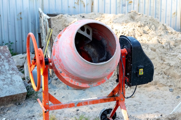 Een betonmixer op het erf van een privélandgoed bij een hoop zand