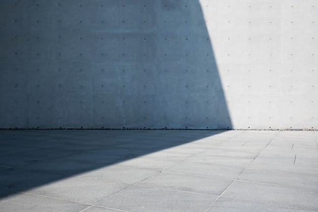 Een betonnen muurachtergrond met een schaduw van een gebouw en een licht erop