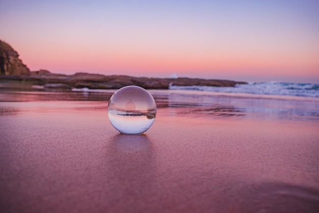 Een betoverend uitzicht op een heldere kristallen bol die tijdens de zonsondergang op het zand bij het strand ligt
