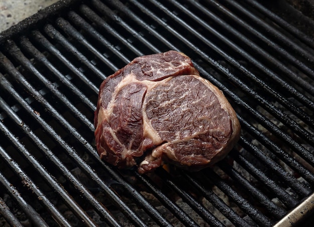 Een biefstuk op een grill met de grill op de achtergrond