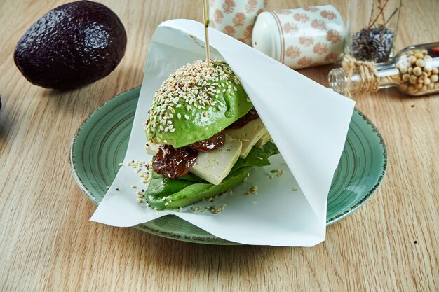 Een bijzondere burger gemaakt van avocadohelften, zoals broodjes met tofu kaas en zongedroogde tomaten. visie. gezond en groen eten. veganistisch