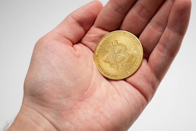 Een bitcoin-munt in de hand. Een man met een gouden munt van de bitcoin-cryptocurrency.