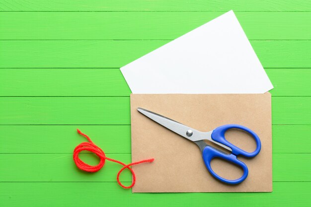 Een blanco vel papier met een envelop op groene houten achtergrond