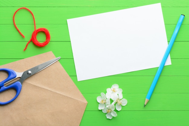 Een blanco vel papier met een envelop op groene houten achtergrond