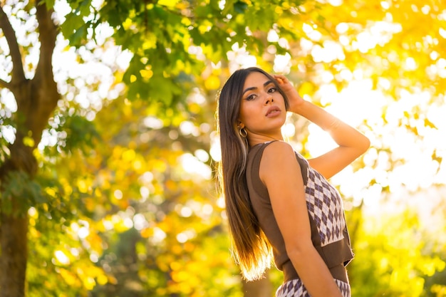 Een blanke brunette vrouw in de herfst bij zonsondergang in een natuurlijk stadspark