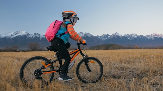 Een blanke kinderen lopen met de fiets in het tarweveld Klein meisje loopt een zwarte oranje cyclus