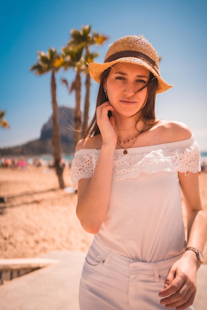 Een blanke roodharige in het wit gekleed en met een strohoed op de stranden van Calpe