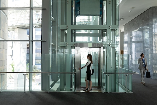 Een blanke vrouwelijke leidinggevende stapt in een moderne lift op kantoor.
