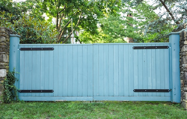 Een blauw hek met een metalen frame en een zwarte deur.