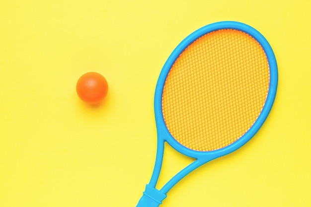Een blauw racket en een oranje bal om op een gele achtergrond te spelen Minimaal sportconcept