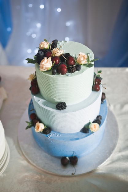 Een blauwe bruidstaart met verse bloemen en bessen staat op tafel 2581