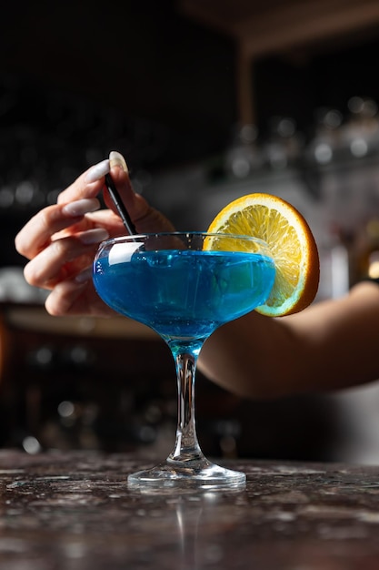 Een blauwe cocktail met een schijfje sinaasappel erbij