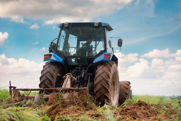 Een blauwe tractor die op landbouwgrond werkt