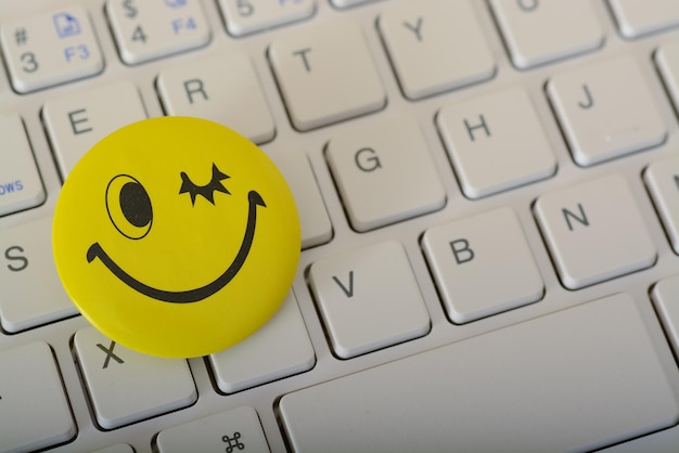 Foto een blij gezicht-emoticon op een laptoptoetsenbord vertegenwoordigt concepten van klantenservice-evaluatie en tevredenheidsenquêtes