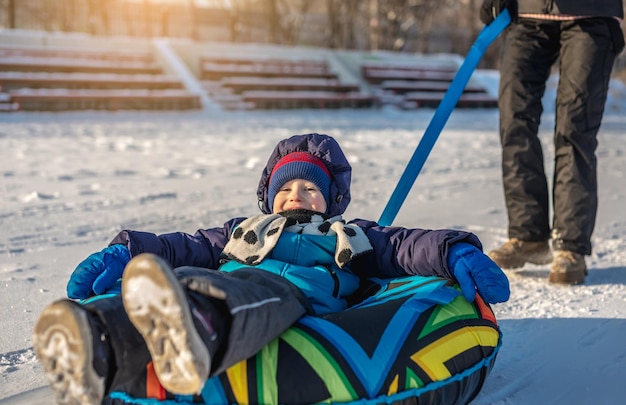 Een blij kind met zijn moeder tubing met een park van een glijbaan Een leuk winterweekend in het park buiten
