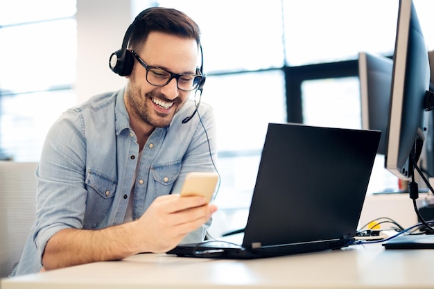 Een blije klantenservicemedewerker kijkt naar de telefoon.