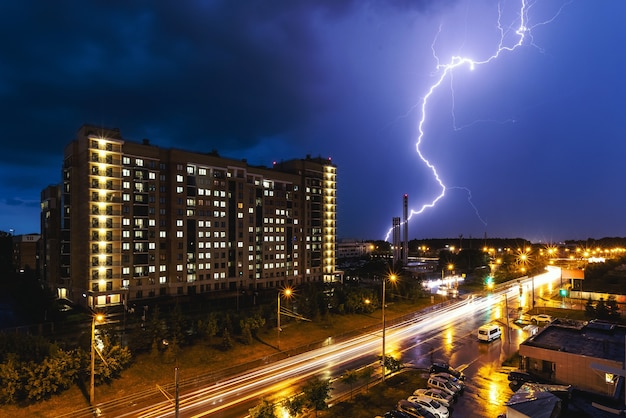 Een blikseminslag tijdens een onweersbui tegen de achtergrond van een stadsgebouw. Nacht stadsverkeer.