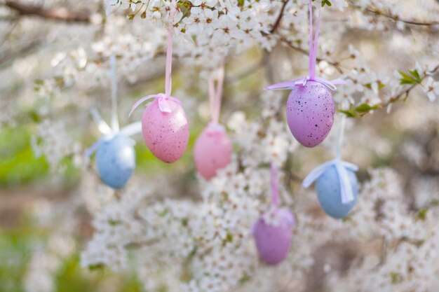 Een bloeiende boom in de tuin is versierd met decoratieve kleurrijke paaseieren. vakantiedecoratie en buitenvieringsconcept