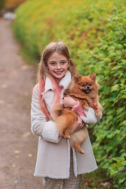 Een blond meisje met een spits in haar armen in het park.