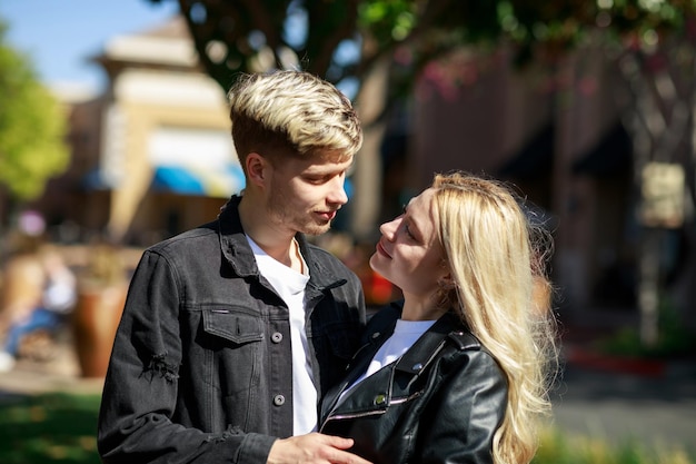 Een blond stel dat in het park staat en elkaar aankijkt op een zonnige dag Foto van hoge kwaliteit