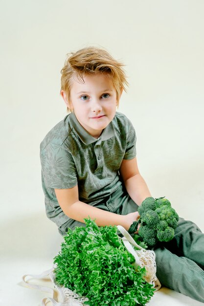 Een blonde jongen houdt sla in zijn hand op een geïsoleerde, goede voeding.