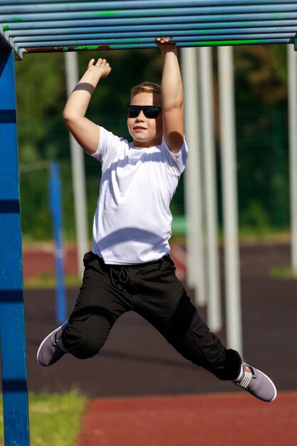 Een blonde jongen met een donkere bril oefent op een sportveld. hoge kwaliteit foto