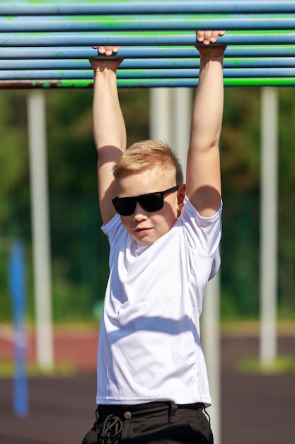 Een blonde jongen met een donkere bril oefent op een sportveld. Hoge kwaliteit foto