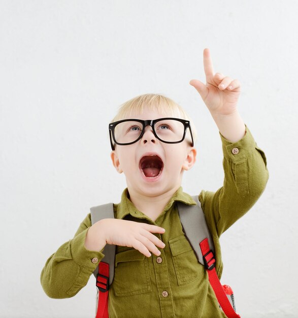 een blonde schooljongen met een bril en een rugzak