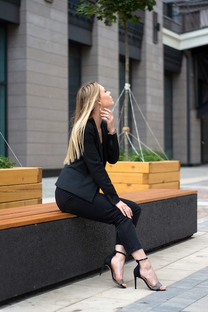 Een blonde vrouw in een zwart pak in de city.businesswoman op een wandeling.